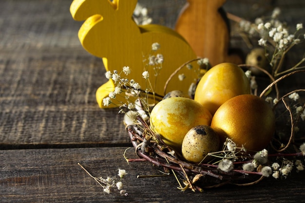 Sfondo delle uova di Pasqua Uova di Pasqua dorate nel nido e decorazione pasquale su tavola di legno Spazio di copia