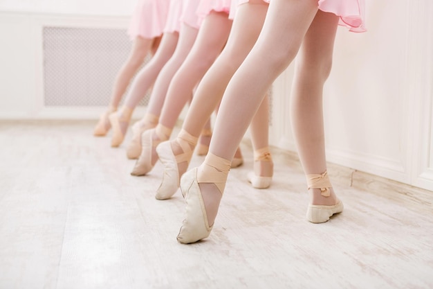 Sfondo di balletto, formazione di giovani ballerine. Gambe di piccoli ballerini in scarpe da punta, facendo esercizi. Scuola di danza classica, copia spazio