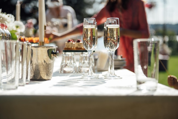 Sfondo di bicchiere di vino Tavolo per banchetti alcolici Celebrazione di eventi all'aperto Bicchieri vuoti di alcol lucidi Abbondanza di bicchiere di vino con bottiglia di vino sullo sfondo Ricevimento di matrimonio