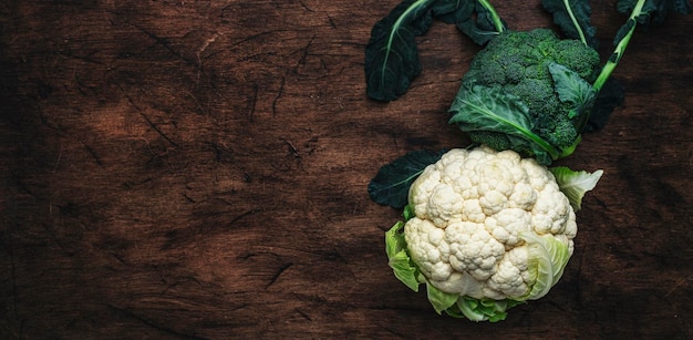 Sfondo di cibo autunnale con cavolfiore e broccoli sul vecchio tavolo da cucina in legno rustico vista dall'alto copia spazio banner