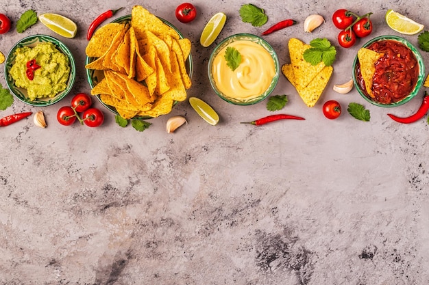 Sfondo di cibo messicano: guacamole, salsa, salse di formaggio con nachos, vista dall'alto.