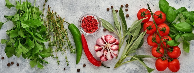 Sfondo di cottura del cibo. Zafferano fresco, aglio, coriandolo, basilico, pomodorini, peperoni e olio d'oliva, spezie erbe e verdure al tavolo di ardesia grigio chiaro. Vista dall'alto degli ingredienti alimentari.