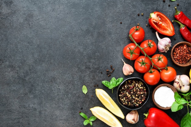 Sfondo di cucina cibo sulla tavola nera. Verdure fresche, spezie, erbe aromatiche. Ingredienti per cucinare con spazio per il testo.