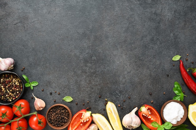 Sfondo di cucina cibo sulla tavola nera. Verdure fresche, spezie, erbe aromatiche. Ingredienti per cucinare