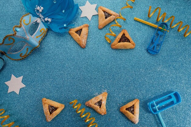 Sfondo di festa ebrea con hamantaschen o hamans orecchie cookie maschera di carnevale e noisemaker