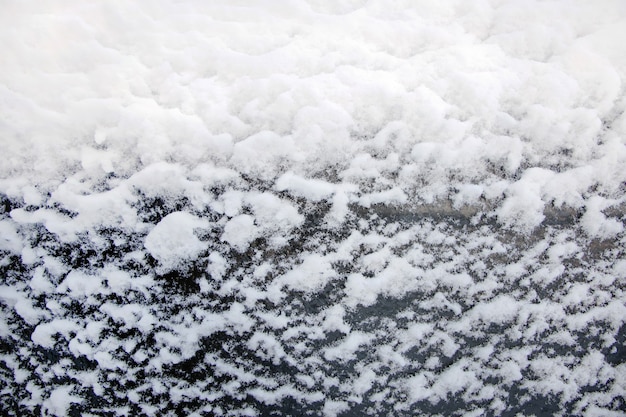 Sfondo di fiocchi di neve bianchi su vetro nero, primo piano