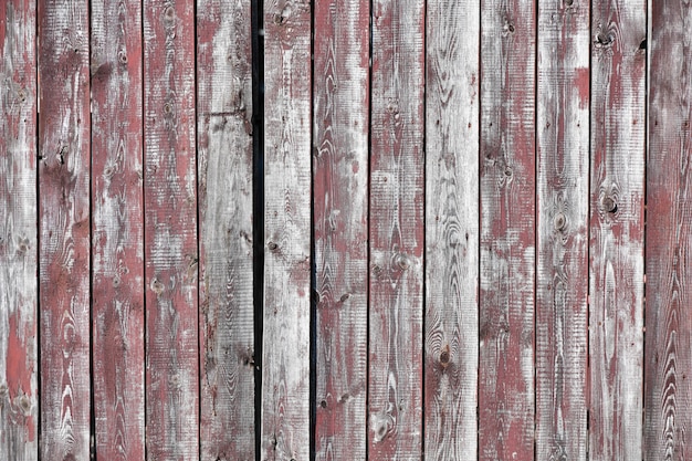 Sfondo di legno rosso-grigio. schede verticali. la vecchia vernice si stacca. vecchie schede. Struttura di legno grigia rossa di un bordo dipinto consumato. Struttura di legno grigia rossa del bordo dipinto indossato anziano