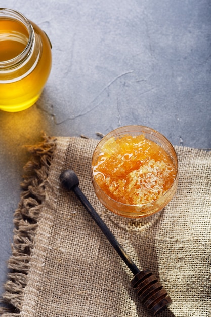 Sfondo di miele Dolce miele nel pettine, vaso di vetro.