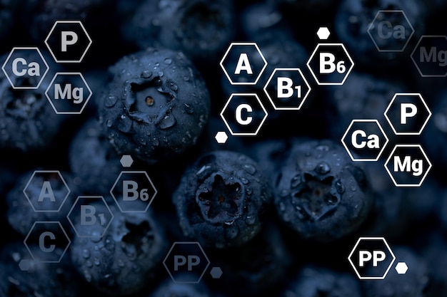 Sfondo di mirtilli freschi con designazioni di lettere di vitamine e minerali Concetto di cibo sano vegano e vegetariano
