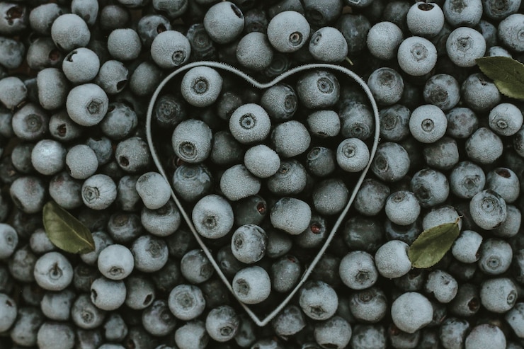 Foto sfondo di mirtilli freschi congelati a forma di cuore in metallo. texture di mirtilli close-up. la raccolta estiva dei frutti di bosco. spazio per il testo