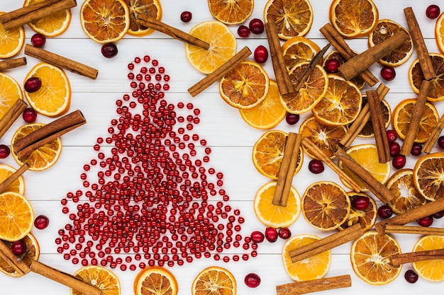 Sfondo di natale. Albero di Natale, arance, cannella, mirtillo rosso, fondo di legno bianco