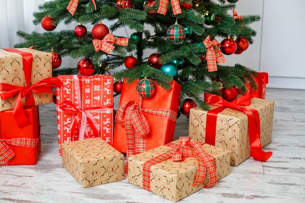 Sfondo di Natale: albero verde decorato con palline rosse e verdi, decorazioni natalizie, ghirlande gialle. Nuovo anno. Regali sotto l'albero per le feste