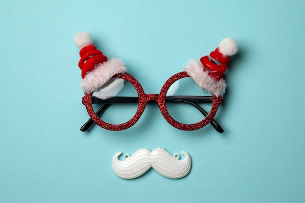 Sfondo di Natale blu con occhiali Santa e baffi bianchi hipster.