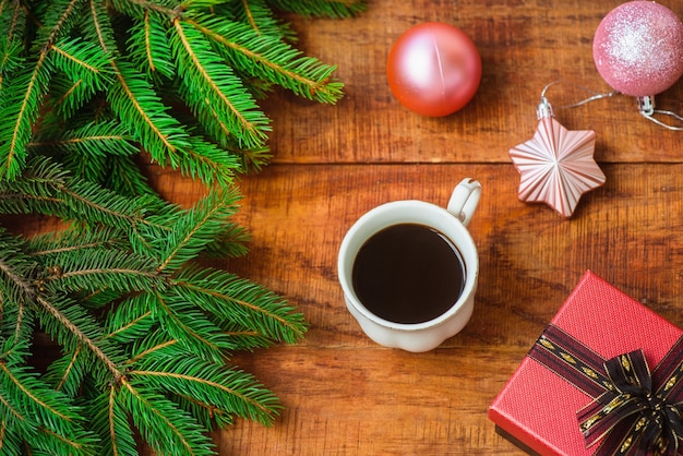 Sfondo di Natale Composizione di rami di abete Palle di Natale, tazza con caffè e regalo su uno sfondo di legno