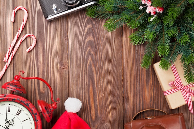 Sfondo di Natale con fotocamera, sveglia e ramo di un albero sul tavolo di legno. Vista dall'alto con copia spazio