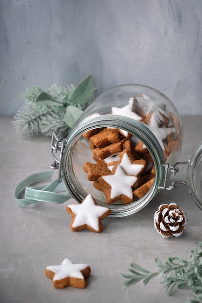 Sfondo di Natale con gustosi biscotti allo zenzero stella in un barattolo di vetro con decorazioni floreali invernali