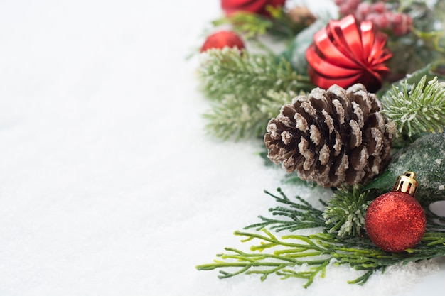 Sfondo di Natale con palline, rami di abete verde, pigne, su sfondo bianco neve.