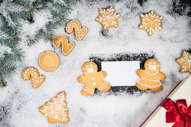 Sfondo di Natale con pan di zenzero sulla neve invernale. Carta d'atmosfera per le vacanze. Vista dall'alto, copia dello spazio. Tradizioni familiari, bricolage, concetto di celebrazione. Sfondo festivo con biscotti di panpepato fatti in casa.