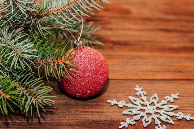 Sfondo di Natale con rametto di abete e giocattoli rossi su tavole di legno.