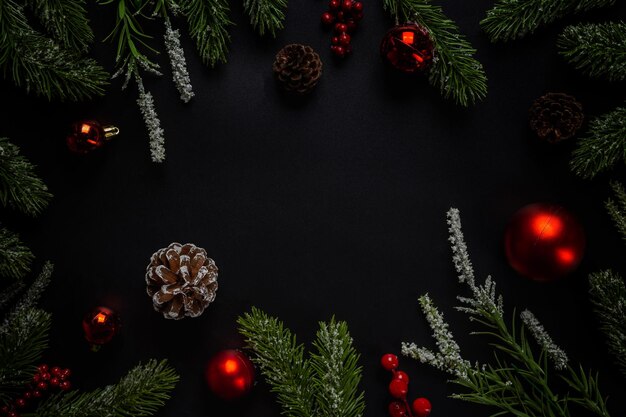 Sfondo di Natale con rami di abete e palla rossa su sfondo scuro e nero. Vista dall'alto con copia spazio