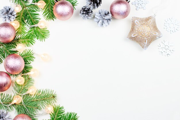 Sfondo di Natale con rami di abete, luci di Natale, decorazioni rosa e beige, ornamenti d'argento