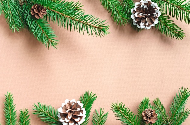Sfondo di Natale con rami di abete verde con coni e spazio di copia su beige