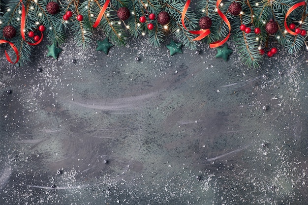 Sfondo di Natale con ramoscelli di abete, palline rosse e verdi e luci sul bordo scuro con texture, copia-spazio