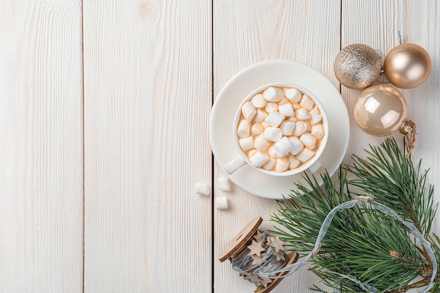 Sfondo di Natale con una tazza di caffè con marshmallow, palline di abete e rami di pino. Vista dall'alto, copia dello spazio.