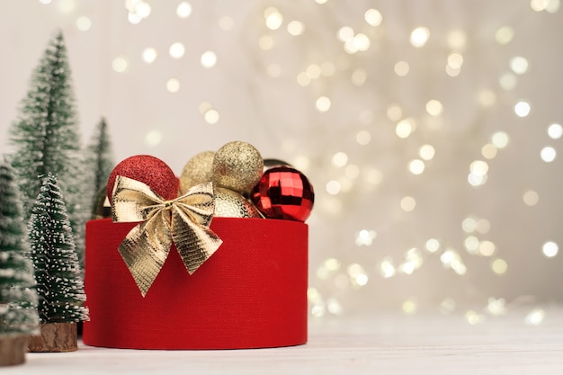 Sfondo di Natale, confezione regalo rossa con un fiocco dorato sullo sfondo del bokeh di Natale. Copia spazio