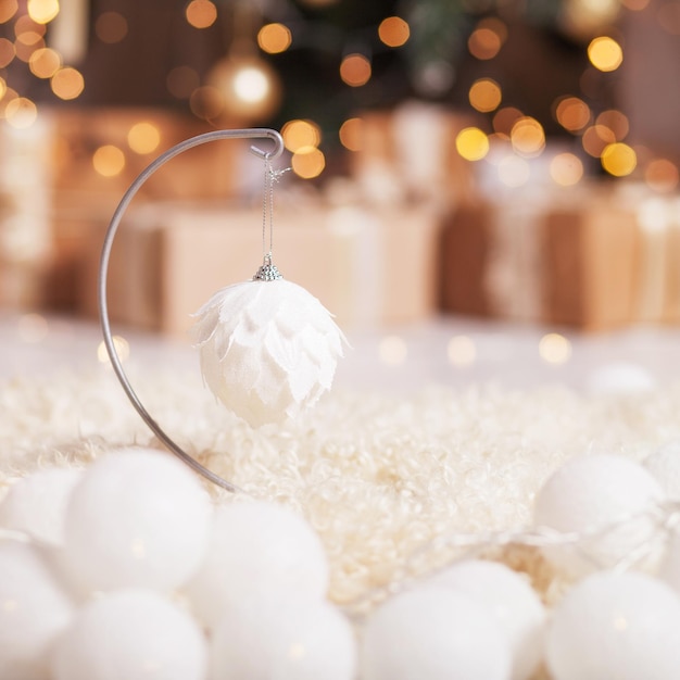 Sfondo di Natale d'epoca. Decorazione di Natale contro le luci della sfuocatura dell'albero di abete. Luna festiva, luce magica. Bianco e oro. Copia spazio, focus selezionato