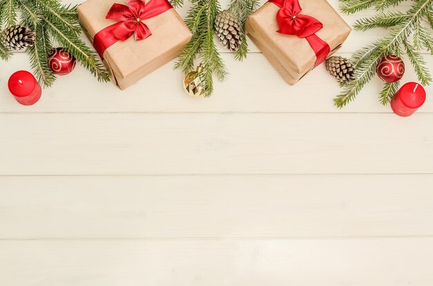 Sfondo di Natale e Capodanno con una composizione di regali, decorazioni per alberi di Natale e rami, candele con spazio per le copie su tavole di legno bianco