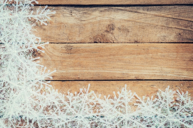 Sfondo di Natale marrone di legno e fiocchi di neve bianchi con spazio.