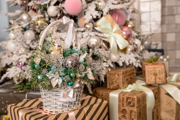 Sfondo di Natale o Capodanno: cestino con giocattoli di vetro colorato e palline, decorazioni e regali su fondo di legno vicino all'albero di Natale. Feste felici.