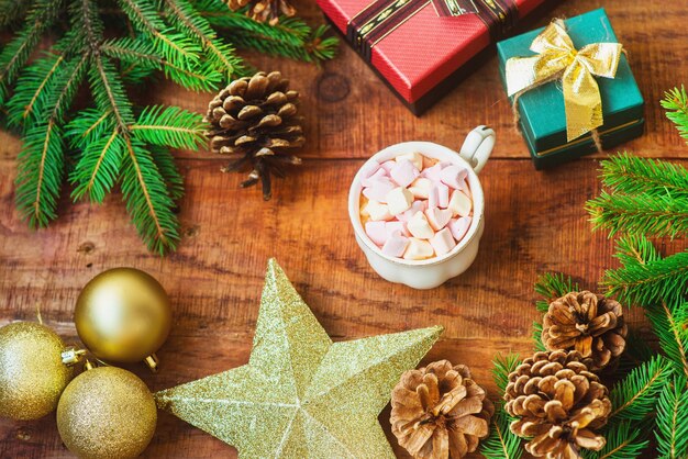 Sfondo di Natale. Rami di abete, palle di Natale e stella, coni e regali e tazza di caffè con marshmallow su fondo di legno. Copia spazio Vista dall'alto. Biglietto di Natale o Capodanno. piatto