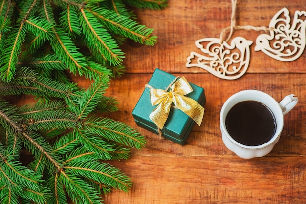 Sfondo di Natale. Rami di abete rosso, figure di uccelli in legno, regalo e tazza di caffè su uno sfondo di legno.