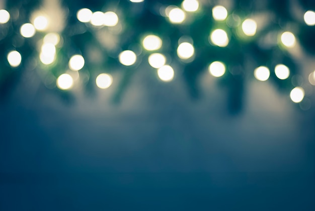 Sfondo di Natale sfocato verde blu scuro con luci di ghirlanda bokeh e bordo di ramoscelli di abete sfocato