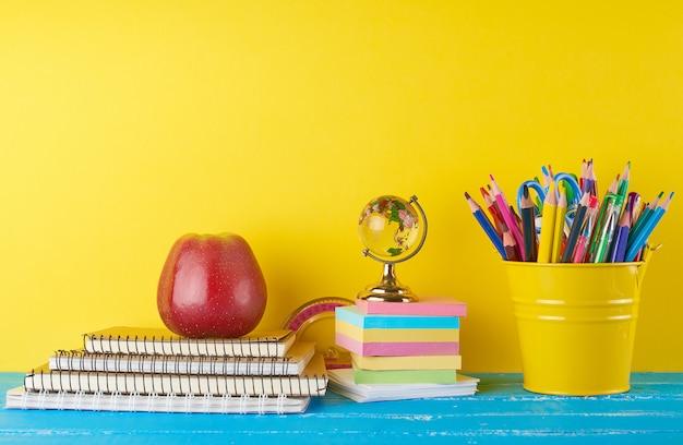 Sfondo di nuovo a scuola con le matite, il blocco note e la mela della cancelleria dei bambini