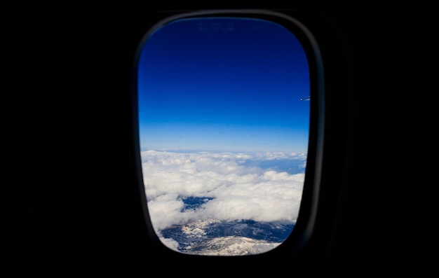 Sfondo di nuvole bianche appeso al cielo blu e copre montagna innevata Foto aerea dal finestrino dell'aereo Sfondo nero