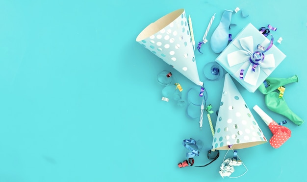 Sfondo di palloncino di compleanno con scatola regalo, stelle filanti colorate, coriandoli e cappelli per feste di compleanno su blu