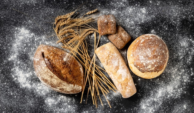 Sfondo di panetteria. Pane croccante appena sfornato e focacce con vista dall'alto di spighe di grano