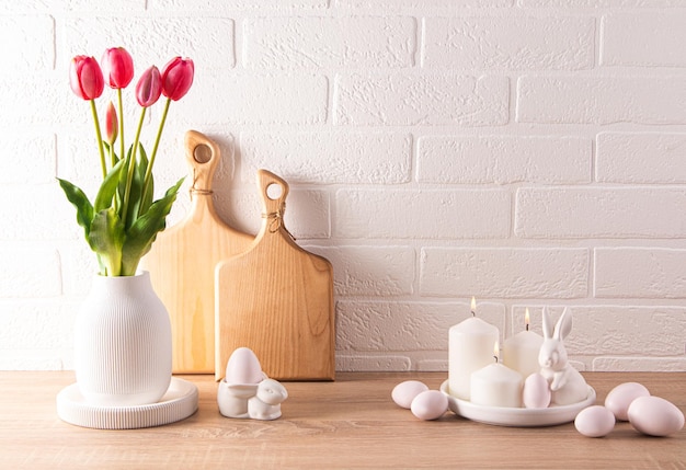 Sfondo di Pasqua vista frontale sul tavolo decorato con fiori in un vaso uova tradizionali e conigli di ceramica spazio per un testo parete di mattoni bianchi