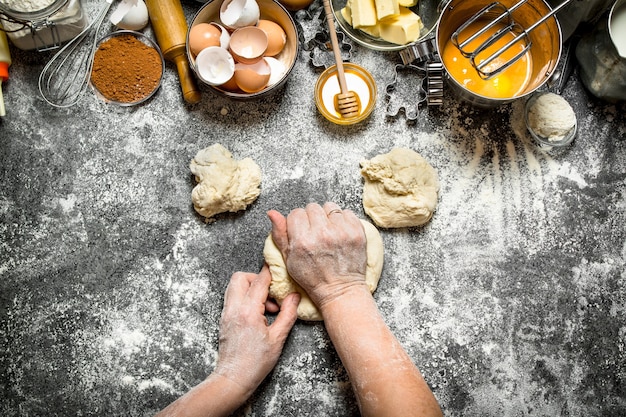 Sfondo di pasta. La donna impasta la pasta con vari ingredienti sul tavolo. Su fondo rustico.