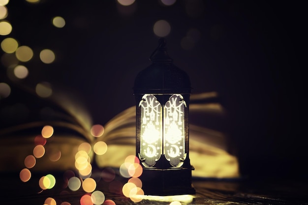 Sfondo di Ramadan Kareem Lanterna araba ornamentale che si illumina e il libro sacro del Corano