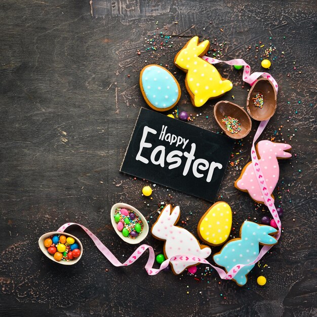 Sfondo di saluto di Pasqua Biscotti di pan di zenzero di Pasqua e uova colorate decorative su sfondo marrone Spazio per la copia gratuita di vista dall'alto