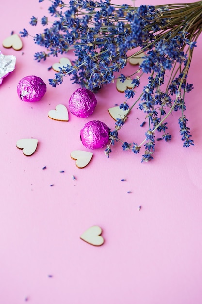 Sfondo di San Valentino. fila di cuori in legno su sfondo rosa, vista laterale di un ramo di lavanda secca. Il giorno di San Valentino concetto. Vista dall'alto, posto per un'iscrizione, pubblicità. Messa a fuoco selettiva