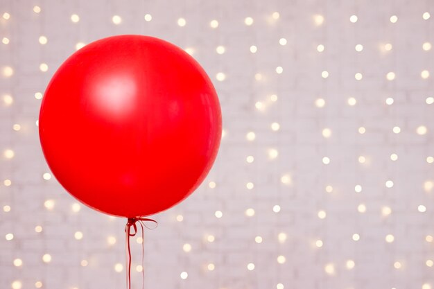 Sfondo di San Valentino - grande palloncino rosso e spazio per la copia su muro di mattoni bianchi con luci
