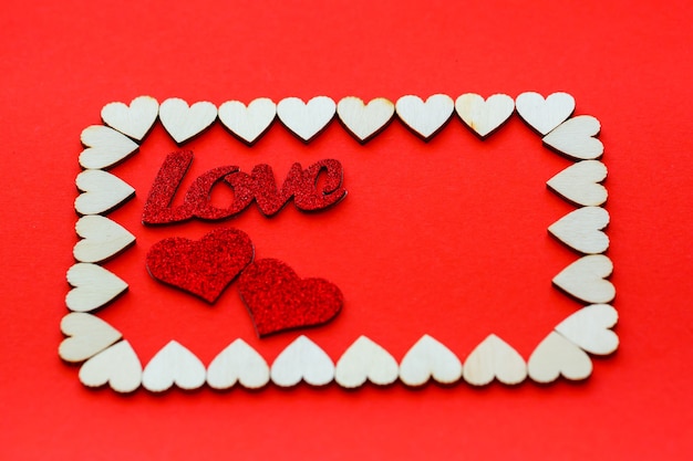 Sfondo di San Valentino. I cuori di legno sono allineati con un rettangolo su uno sfondo rosso con posto per il testo con i cuori. Cuori per cartoline.