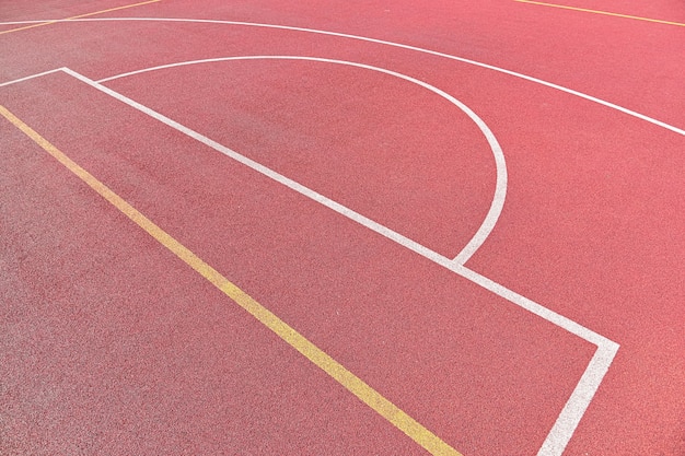 Sfondo di un campo da basket all'aperto rosso con linee di marcatura bianche e gialle, vista dall'alto