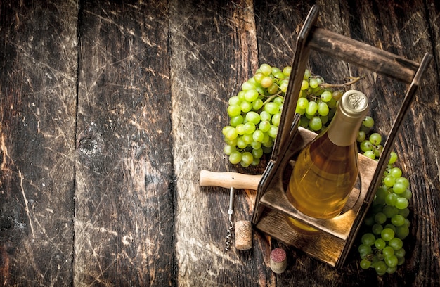 Sfondo di vino. Vino bianco su una bancarella con rami di uva fresca. Su uno sfondo di legno.