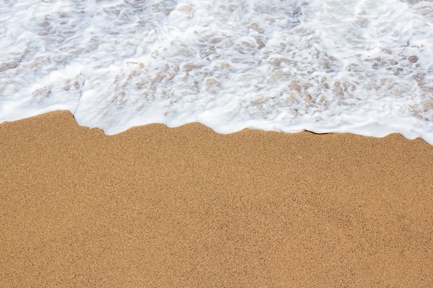 Sfondo estivo - primo piano di sabbia dorata e acqua di mare sulla spiaggia